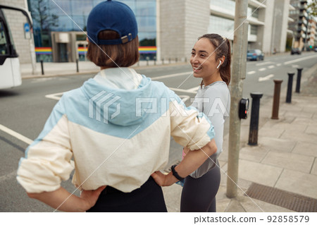 Two sportive young female friends walking city after morning running 92858579