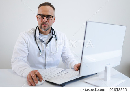Portrait of a male doctor who works in the office at the computer 92858823