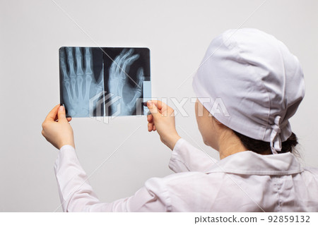 A doctor or radiologist holds an X-ray of a patient with a hand injury. Diagnosis of fractures, fractures of bones and dislocations of the joints of the arm. 92859132