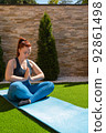 young woman practising meditation in the garden in the open air, relaxation exercises, doing the lotus posture. vertical. concept of health and well-being. 92861498