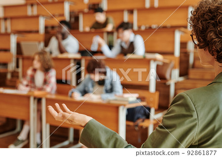 Young confident college teacher or lecturer explaining one of lesson points Young confident college teacher or lecturer explaining one of lesson points 92861877