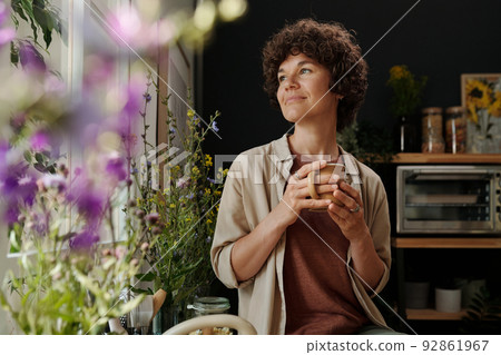 Young contemporary woman in home wear looking through kitchen window 92861967