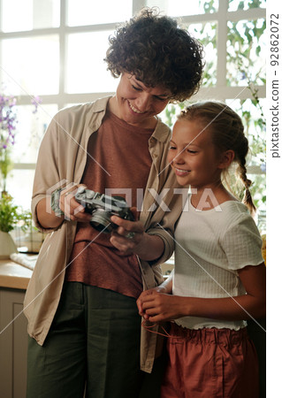 Young smiling woman in casualwear showing new photos to her daughter 92862072