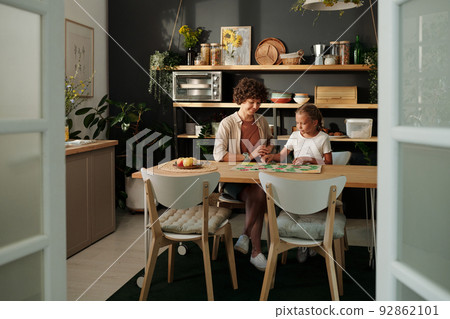 Young woman and her youthful daughter playing board game togather Young woman and her youthful daughter playing board game togather 92862101