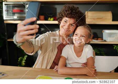 Happy young family of mother and daughter with smartphone making selfie Happy young family of mother and daughter with smartphone making selfie 92862107