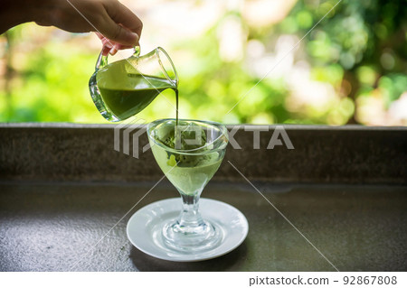 Pouring hot fudge green tea over matcha ice cream in glass Pouring hot fudge green tea over matcha ice cream in glass 92867808