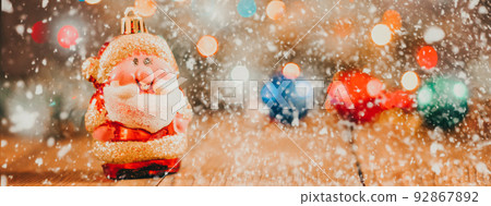 Christmas background with gift boxes, santa claus toy on wooden background with garland bokeh. Festive winter concept. Flat lay, copy space. photo banner 92867892