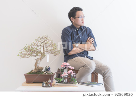 Mini bonsai tree in the flowerpot and a man 92869020