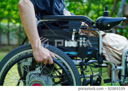 Asian elderly woman disability patient sitting on electric wheelchair in park, medical concept. Asian elderly woman disability patient sitting on electric wheelchair in park, medical concept. 92869109