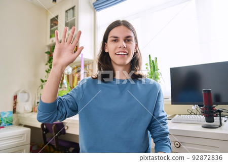 Handsome teenage male waving hand looking at webcam 92872836