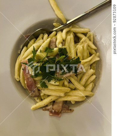 Pasta Carbonara is placed on a white plate with a large margin. Topped with herbs. Pasta Carbonara is placed on a white plate with a large margin. Topped with herbs. 92873109