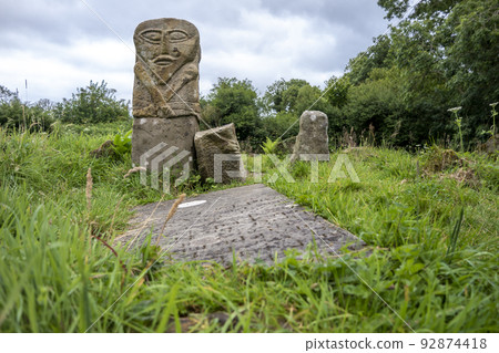 This is a bronze age stone carviing with two faces,called Janus, located In Caldragh Cemetery on Boa Island, Lower Lough Erne. Northern Ireland 92874418