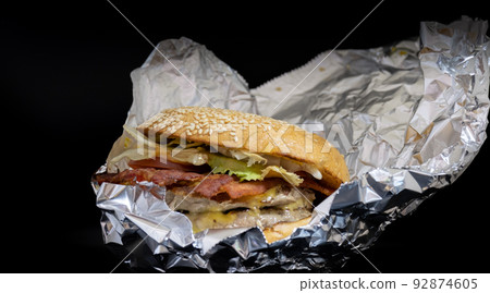 Closeup of big beef hamburger in food wrapping foil .. Closeup of big beef hamburger in food wrapping foil .. 92874605