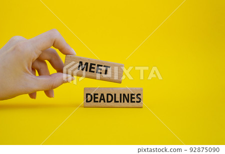 Meet Deadlines symbol. Concept word Meet Deadlines on wooden blocks. Beautiful blue background. Businessman hand. Business and Meet Deadlines concept. Copy space 92875090