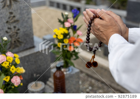 A man visiting a grave and holding hands 92875189