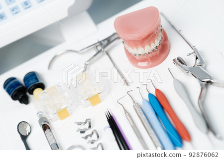Tooth model with metal braces lying on a dental table with instruments 92876062