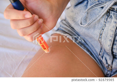 Close-up of a girl using an insulin pen to inject insulin into her leg at home. Close-up of a girl using an insulin pen to inject insulin into her leg at home. 92879565