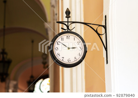 Old analog clock on building wall outdoors 92879840