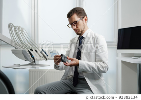 Dentist looking at photopolymer jaw printed on a 3d printer. 92882134