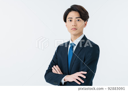 A young man in a suit with his arms crossed in a white background 92883091