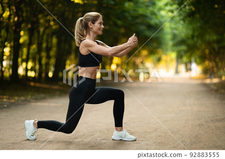 Slim blonde woman exercising at park, copy space 92883555