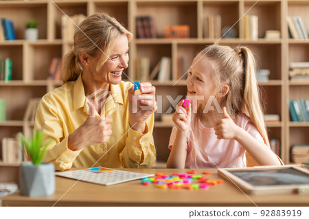 Friendly speech therapist curing child's problems, cute girl learning letters R and U with private tutor Friendly speech therapist curing child's problems, cute girl learning letters R and U with private tutor 92883919