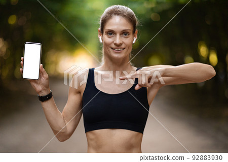 Positive sporty blonde lady showing smartphone with empty screen Positive sporty blonde lady showing smartphone with empty screen 92883930