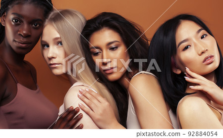 young pretty african and caucasian women posing cheerful together on brown background, lifestyle diverse nationality people concept close up 92884054
