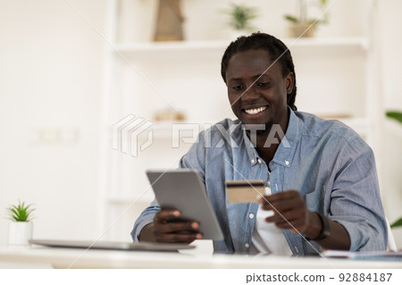 E-Commerce Concept. Smiling Black Man Using Digital Tablet And Credit Card E-Commerce Concept. Smiling Black Man Using Digital Tablet And Credit Card 92884187