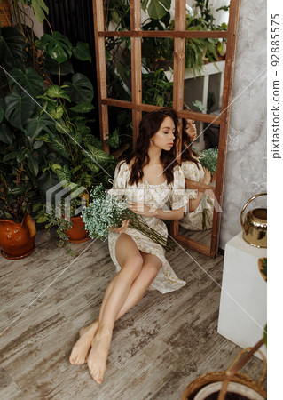 Beautiful girl in a dress sits on a chair Beautiful girl in a dress sits on a chair 92885575