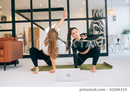 Two charming sports women, do yoga poses, exercises at home Two charming sports women, do yoga poses, exercises at home 92886354