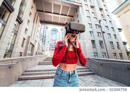 Woman in a virtual reality helmet walks down the street 92886799
