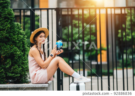 Beautiful young woman holds a small globe in her hands. Beautiful young woman holds a small globe in her hands. 92886836