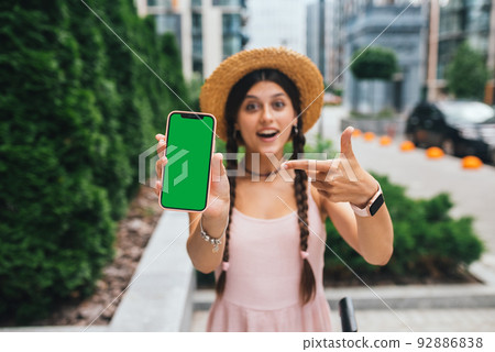 woman showing modern smartphone with green screen for replacement woman showing modern smartphone with green screen for replacement 92886838