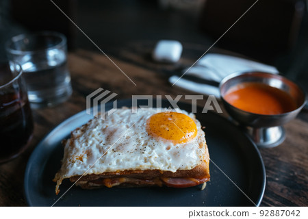 Toast with cheese and sausage covered with fried egg 92887042