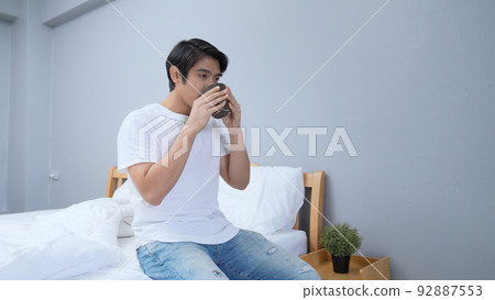 Holiday concept of 4k Resolution. Asian man drinking coffee happily in bedroom. fresh scent. Holiday concept of 4k Resolution. Asian man drinking coffee happily in bedroom. fresh scent. 92887553