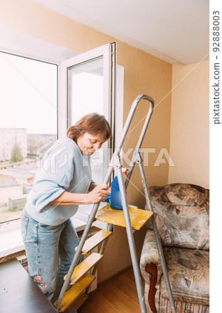 Happy Shy Mature Woman Cleaning House. Concept Of Household And People In Retirement. Elderly Woman Cleaning Apartment. Independent Senior Woman On Stepladder. Housewife. Caucasian Woman Middle Age Happy Shy Mature Woman Cleaning House. Concept Of Household And People In Retirement. Elderly Woman Cleaning Apartment. Independent Senior Woman On Stepladder. Housewife. Caucasian Woman Middle Age 92888003