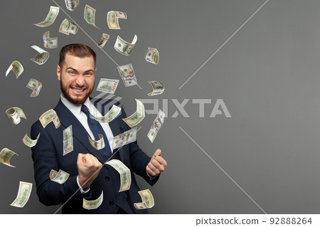 Portrait of happy man screaming under money rain falling down dollar bills banknotes isolated  92888264
