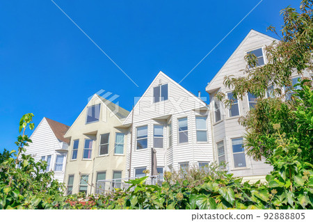 Adjacent traditional houses with gable roofs against the clear blue sky at San Francisco, California 92888805