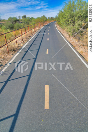 Asphalt road with broken yellow lines in the middle at Sweetwater Wetlands in Tucson, Arizona 92888998