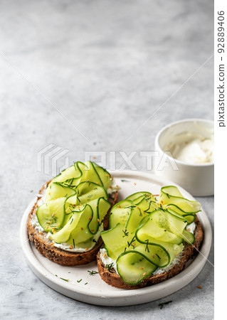 Cucumber sandwiches with soft cheese for delicious healthy vegetarian breakfast on gray background with text space 92889406