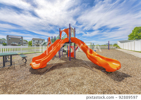 Orange slides in a small playground with picnic table and picket fence at Utah Valley Orange slides in a small playground with picnic table and picket fence at Utah Valley 92889597