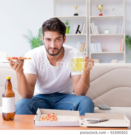 Man eating pizza having a takeaway at home relaxing resting Man eating pizza having a takeaway at home relaxing resting 92890802