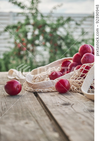 Juicy plums in eco friendly string eco mesh bag on a wooden background 92890948