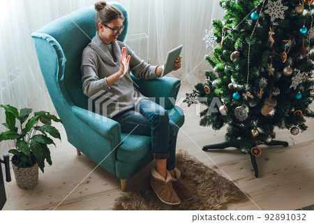 Young woman with tablet on the background of a Christmas tree ac Young woman with tablet on the background of a Christmas tree ac 92891032