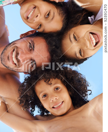 Theyre a close young family. A family of four in swimwear smiling against a bright sky. 92891470