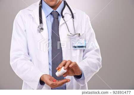 This is the recommend dose. Cropped shot of a doctor emptying a bottle of pills into his hand. This is the recommend dose. Cropped shot of a doctor emptying a bottle of pills into his hand. 92891477