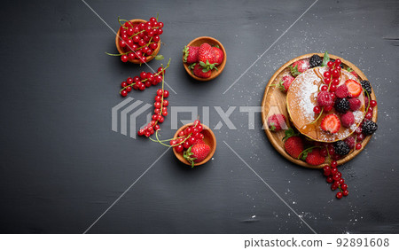 A stack of pancakes with fresh fruits poured with syrup on a black background A stack of pancakes with fresh fruits poured with syrup on a black background 92891608