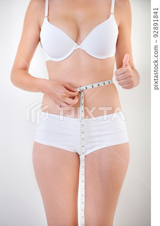 Keeping her weight in check. A young woman in her underwear holding a measuring tape. Keeping her weight in check. A young woman in her underwear holding a measuring tape. 92891841
