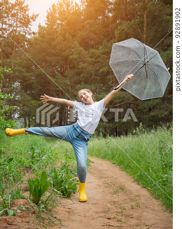 Girl with umbrella poses smiling against green rainy forest 92891902